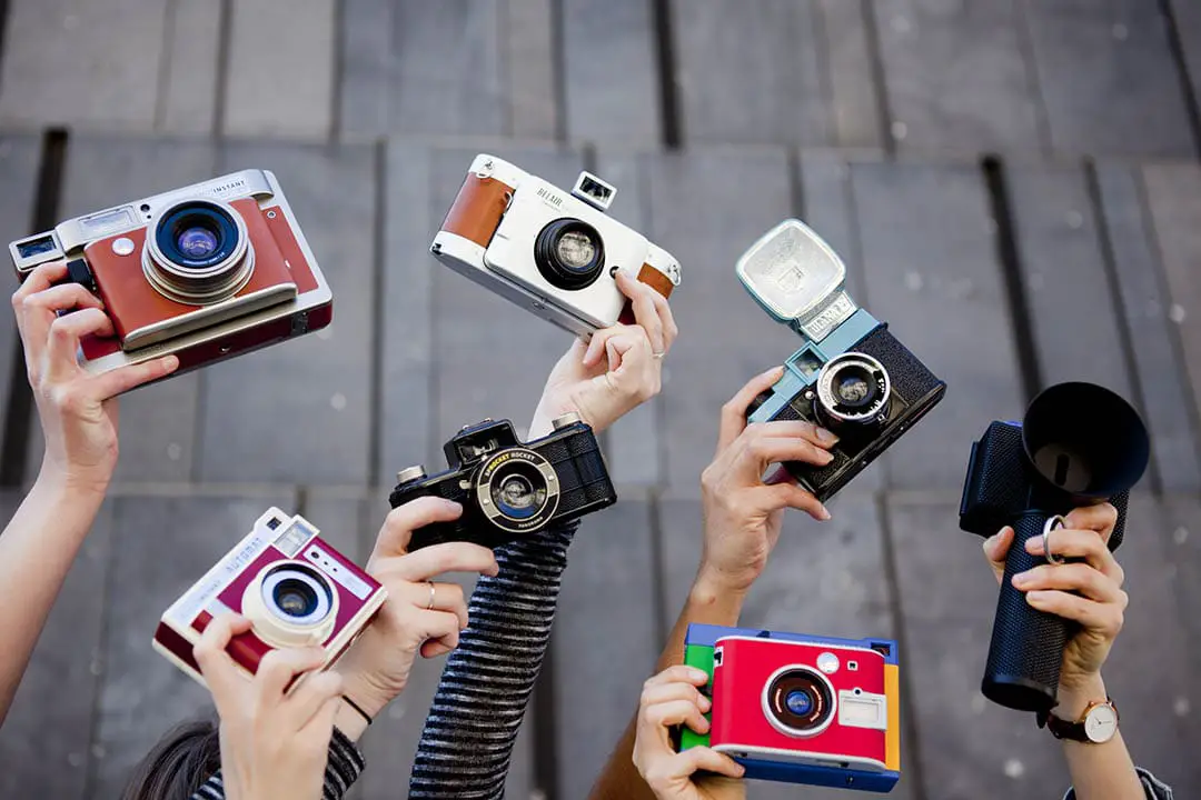 Hands holding up all the Lomography cameras