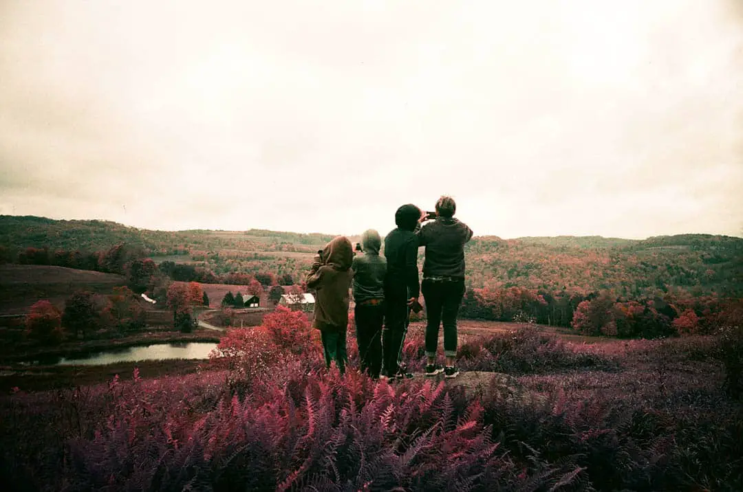 People standing on a hill watching the sunset. Image shot on Lomo Purple changes the green hues to appear red.