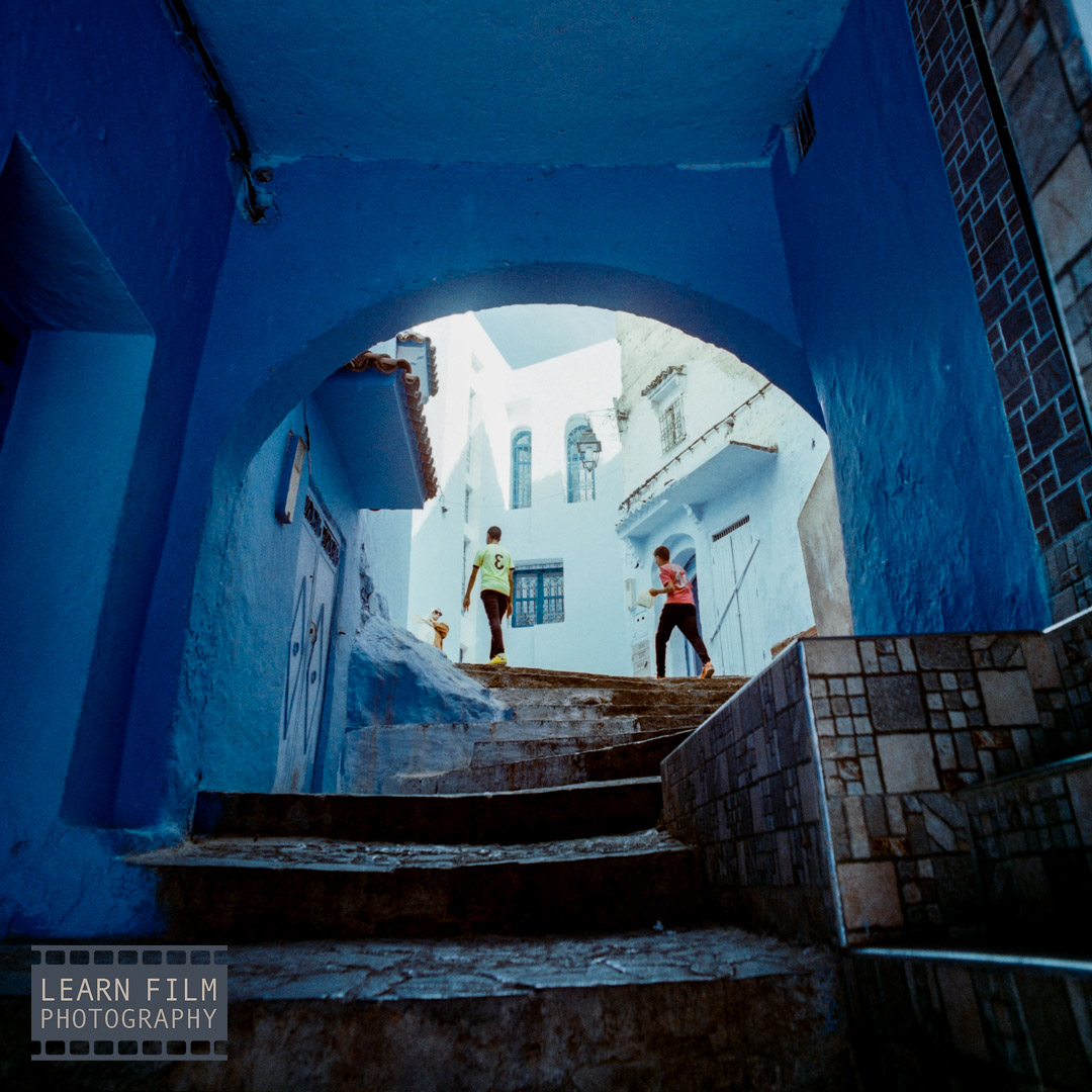 Kids running through the streets of Chefchaouen, captured using a Hasselblad Zeiss Distagon 40mm f/4